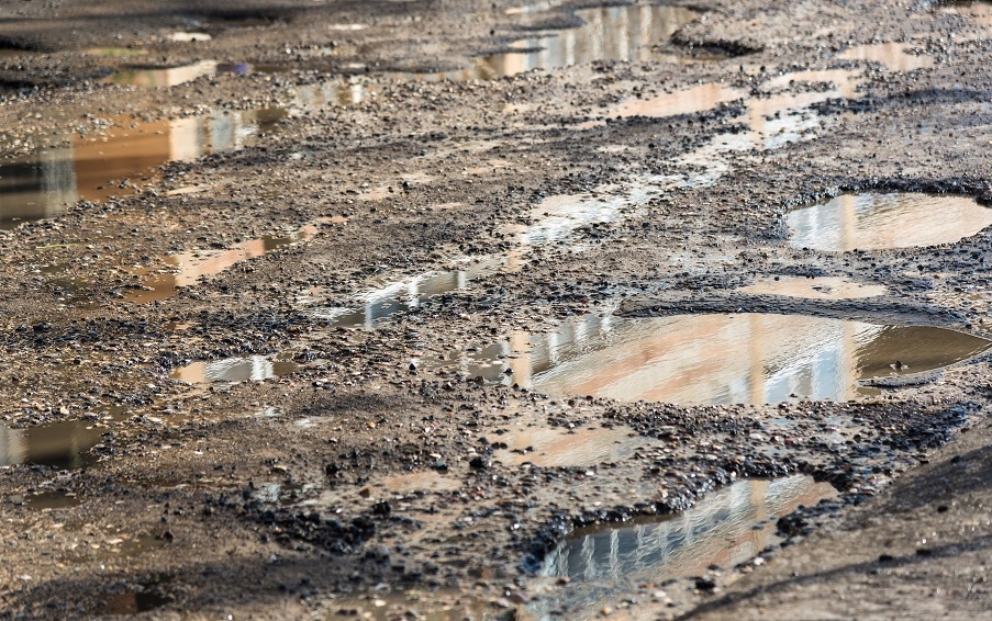 A driveway with muddy puddles