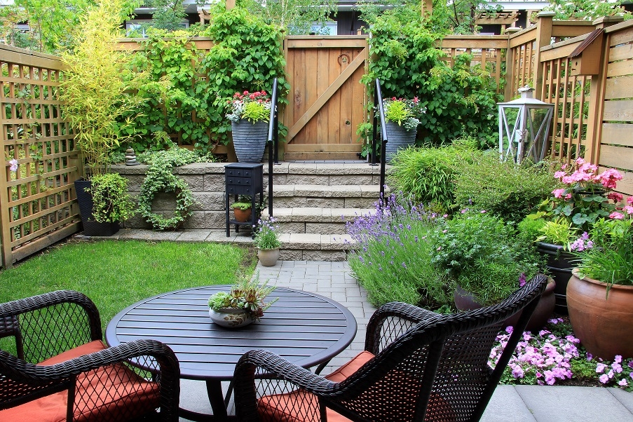 A small city garden with a small lawn and a table and chairs