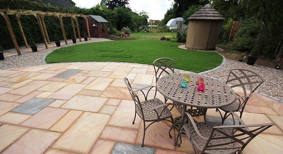 Metal garden furniture on a patio, overlooking a long partially landscaped garden