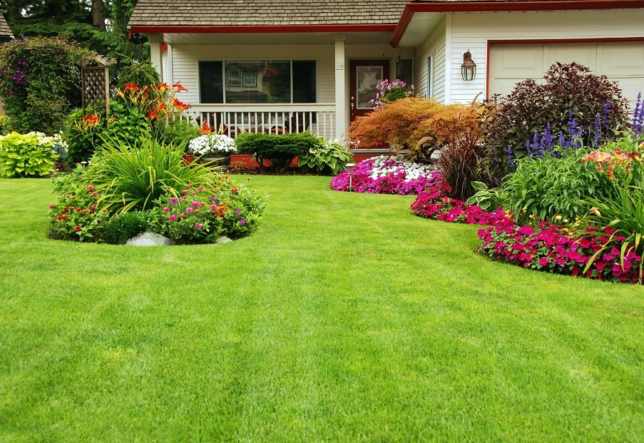 A green, manicured lawn with flower beds