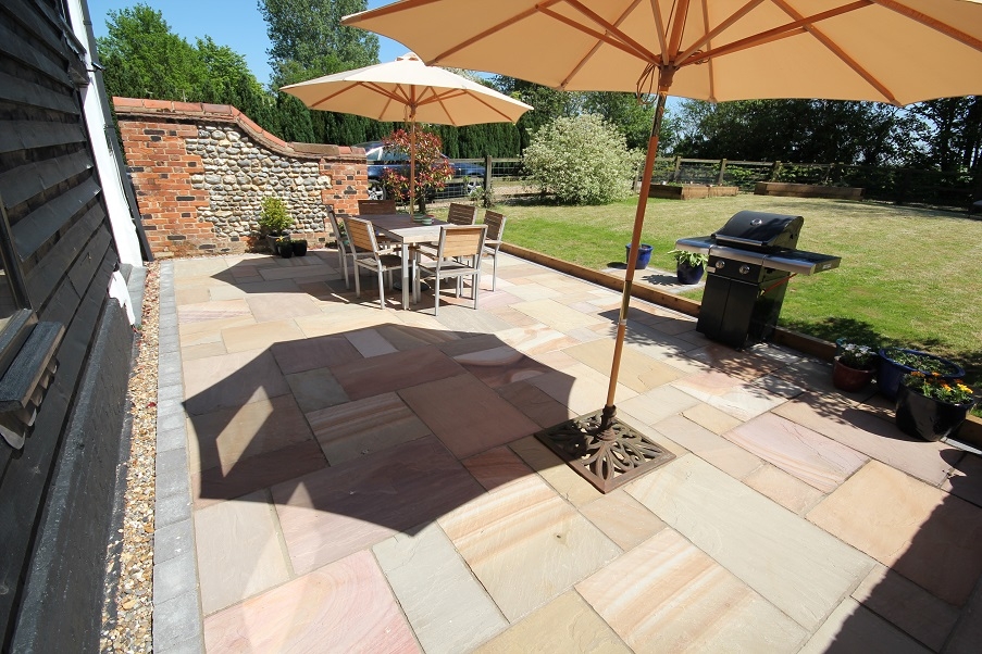 A garden patio with dining chairs and table, designed and landscaped by Knights Paving and Landscaping